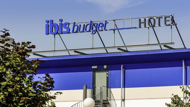 Een hotelschilt met de naam 'ibis budget hotel' en een trap die naar de ingang leidt.