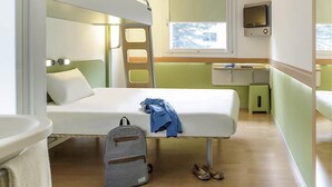 A compact room with bunk beds, a small desk, a TV, and a window with a view. - Ibis Budget Augsburg Gersthofen (Gersthofen)