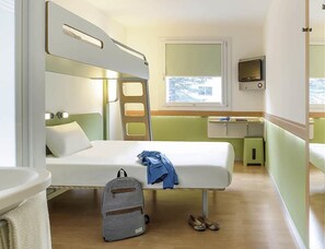 A compact room with bunk beds, a small desk, a TV, and a window with a view. - Ibis Budget Augsburg Gersthofen (Gersthofen)