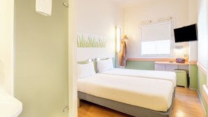 A hotel room with two beds, a desk, a television, and a window. - ibis budget Madrid Calle Alcalá (Madrid)