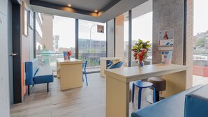 A modern interior with a reception desk, seating area, and large windows offering views of the city. - ibis budget Madrid Calle Alcalá (Madrid)