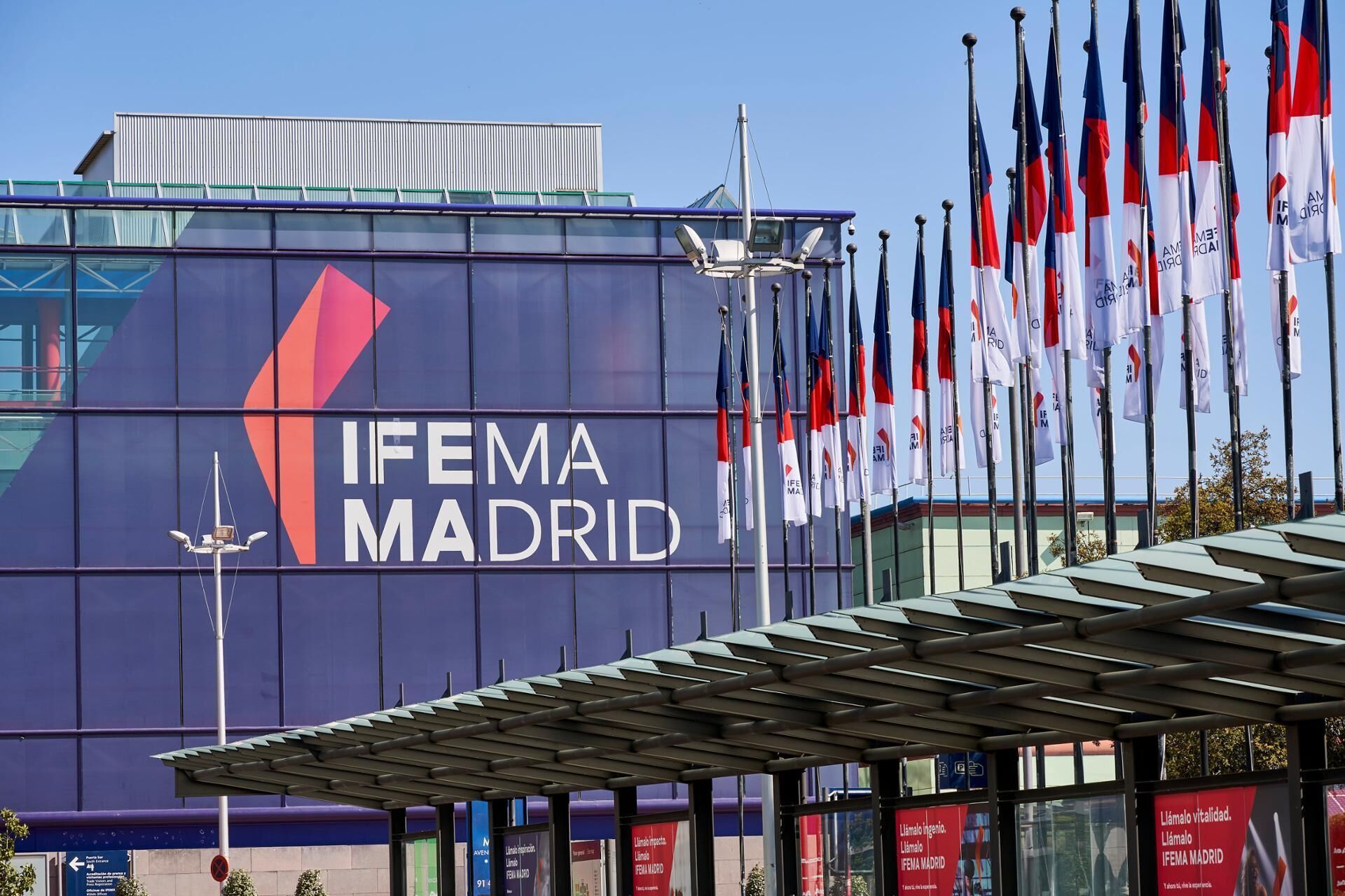 A building with 'IFEMA MADRID' signage, multiple flags, and a modern architectural design.