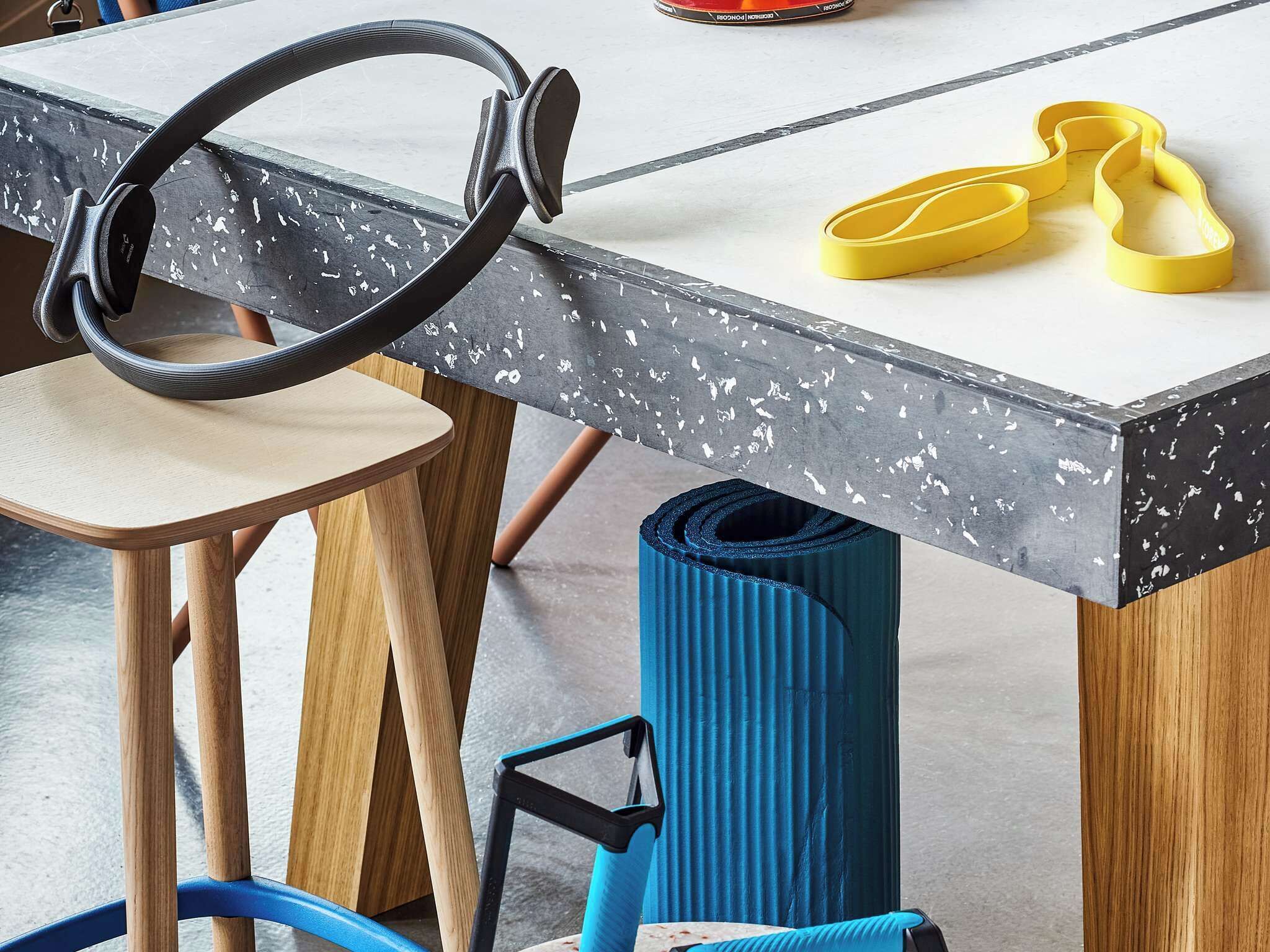 A table with a metal frame, a pair of yellow shoes, and a blue yoga mat.