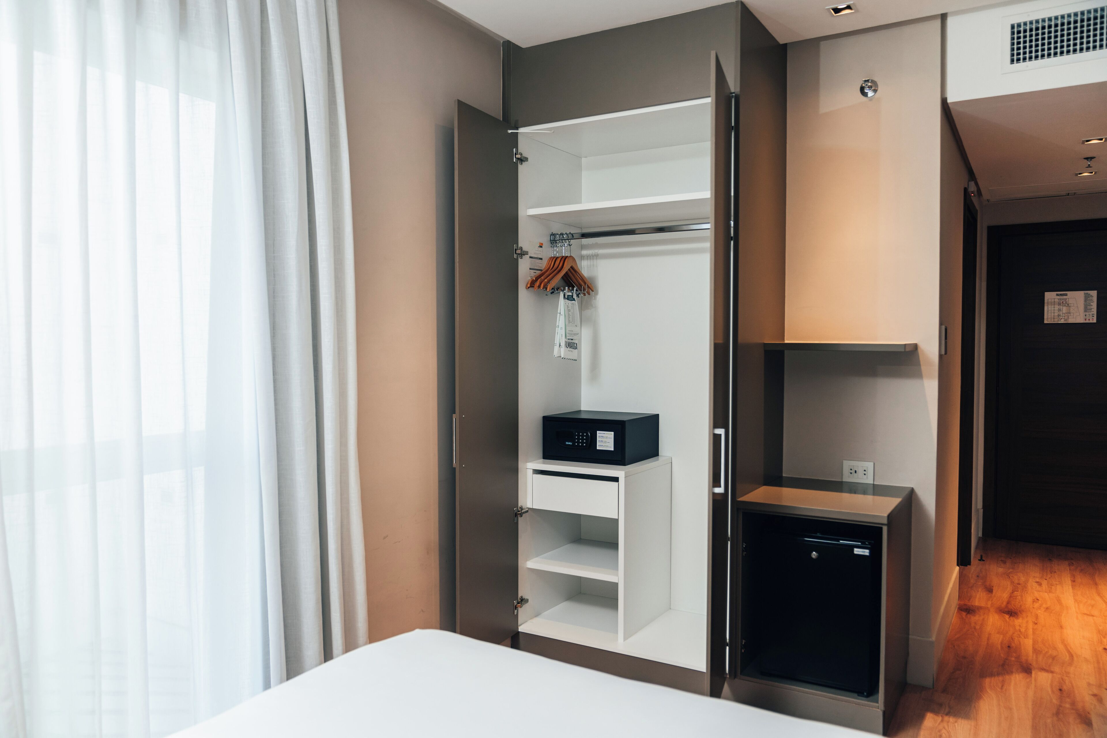 A modern bedroom with a bed, a wardrobe with a built-in heater, and a small desk with a heater.
