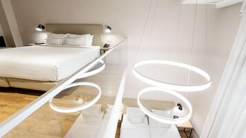 A modern hotel room with a large bed, bedside tables, and a unique circular light fixture.