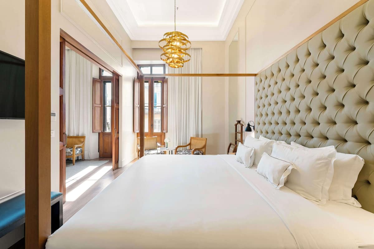 A large bed with a tufted headboard, a bedside table, and a hanging light fixture.