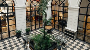 A spacious indoor area with checkered flooring, multiple seating arrangements, and large windows.
