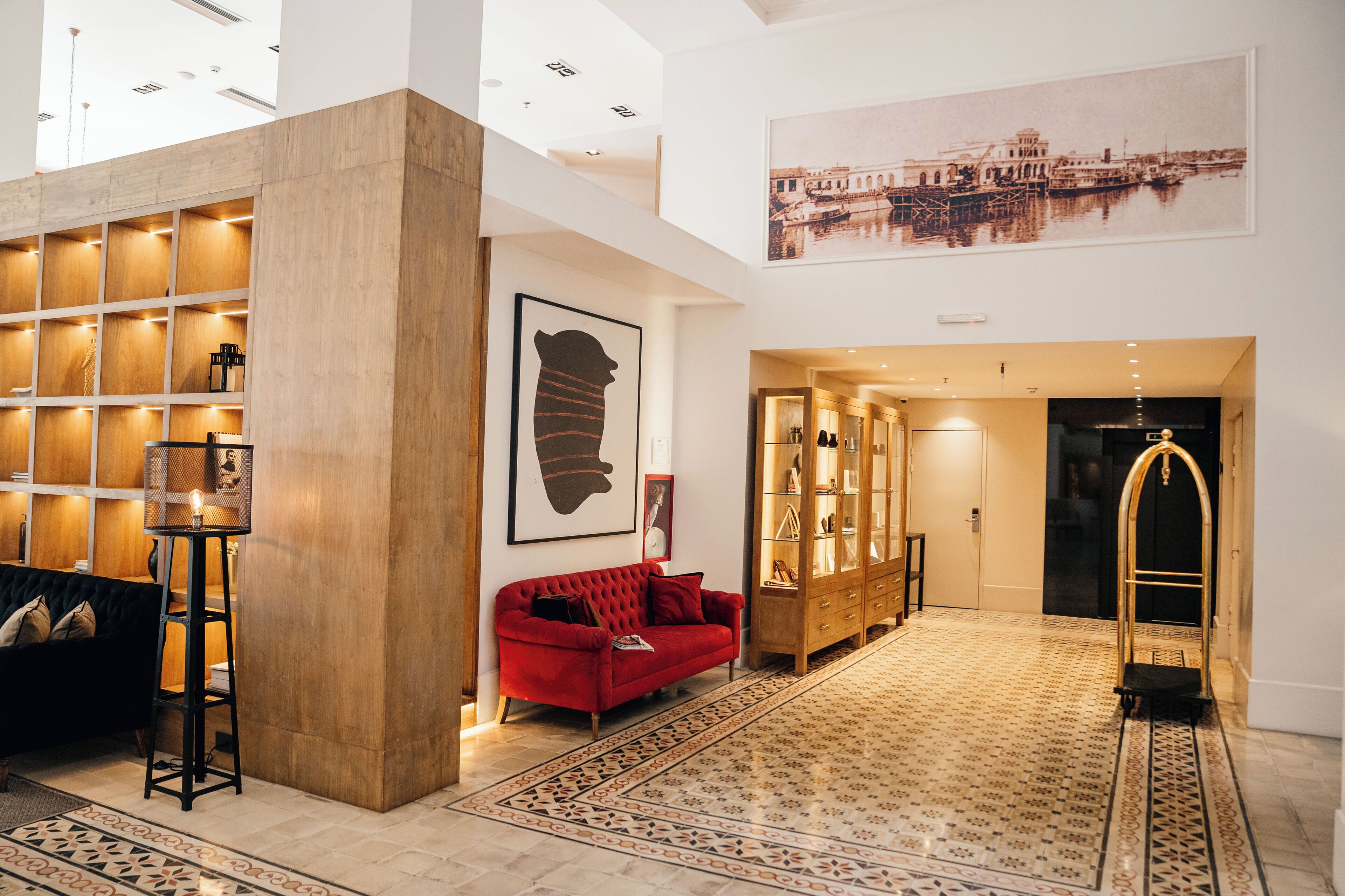 A spacious lobby with a red sofa, a wooden bookshelf, a patterned rug, and a large framed picture on the wall.