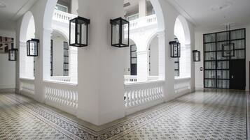 Un interior espacioso con columnas blancas, baldosas de diseño y faroles negros.