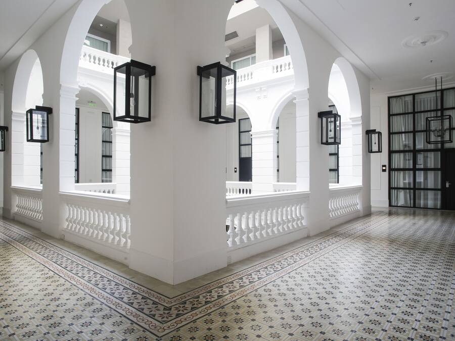 Un interior espacioso con columnas blancas, baldosas de diseño y faroles negros.