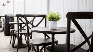 A row of black metal chairs and tables with a potted plant on one table. - The Hotel Hollywood (Los Angeles)