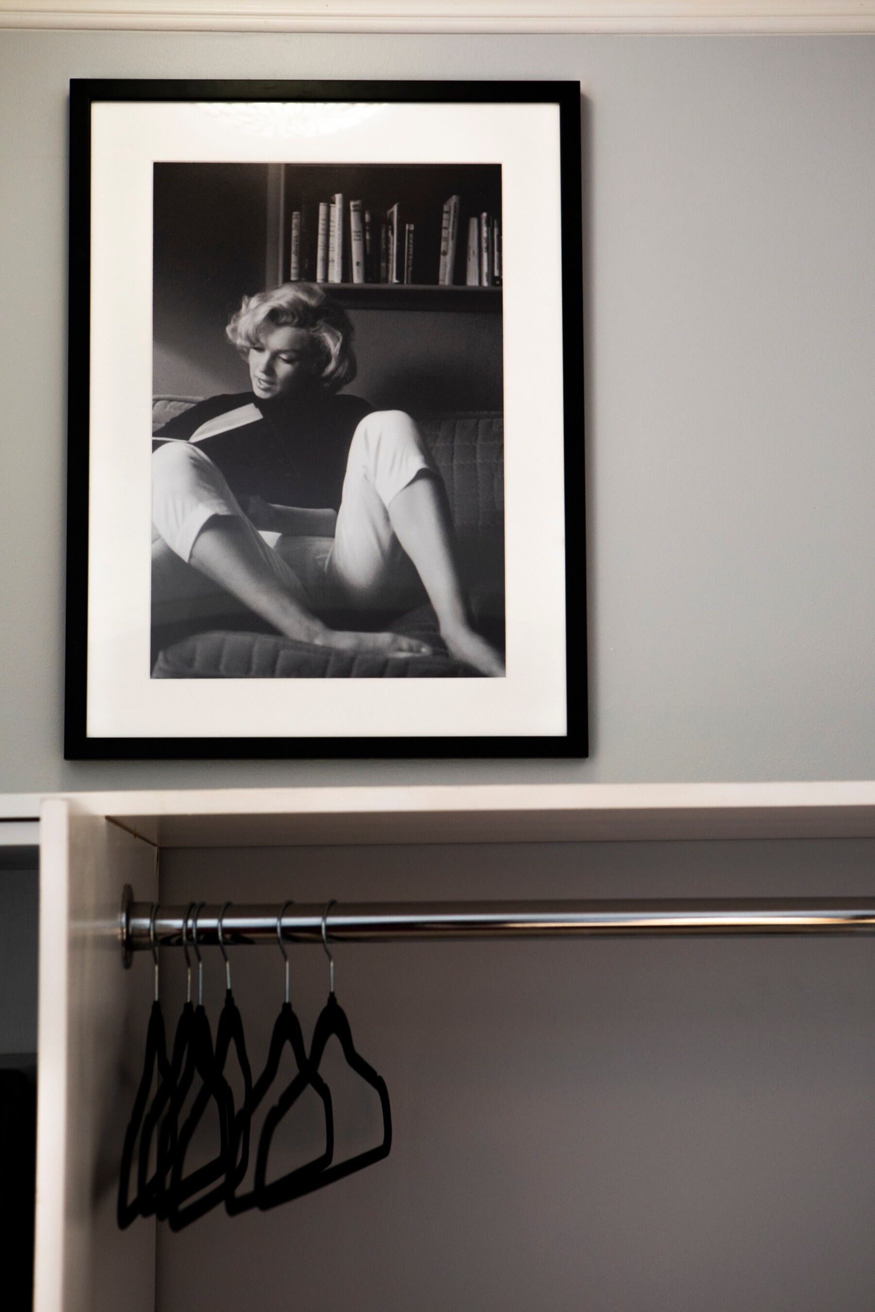 A framed photograph of a person sitting on a couch with a bookshelf in the background.