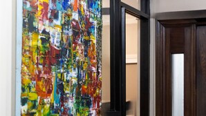 A hallway with a colorful abstract painting on the wall, a wooden door, and a doormat with the text 'HOTEL'. - The Hotel Hollywood (Los Angeles)