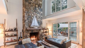 Amplia sala de estar con chimenea de piedra, sofás de cuero y una mesa de centro de madera.