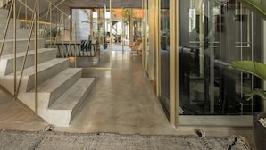 Un interior moderno con una escalera de hormigón, paredes de cristal y una zona de estar central.