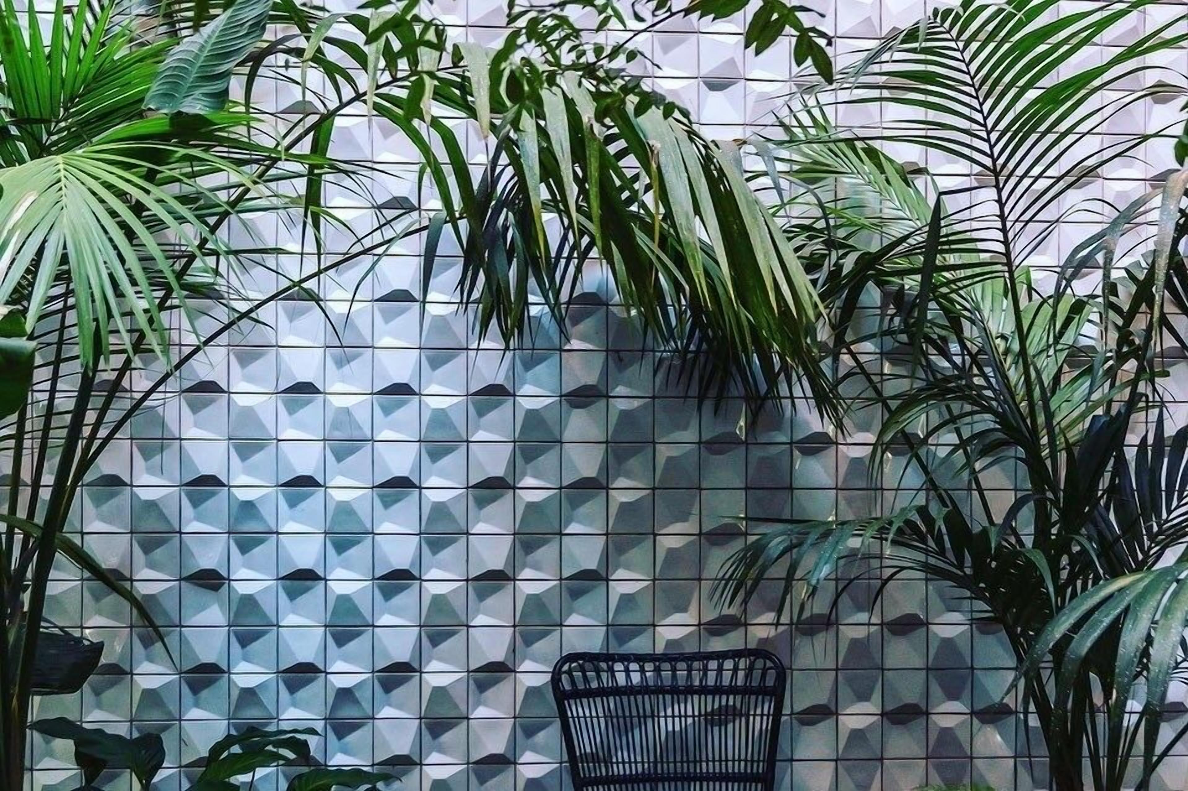 Eine Wand mit einem geometrischen Fliesendesign und ein schwarzer Metallstuhl davor.