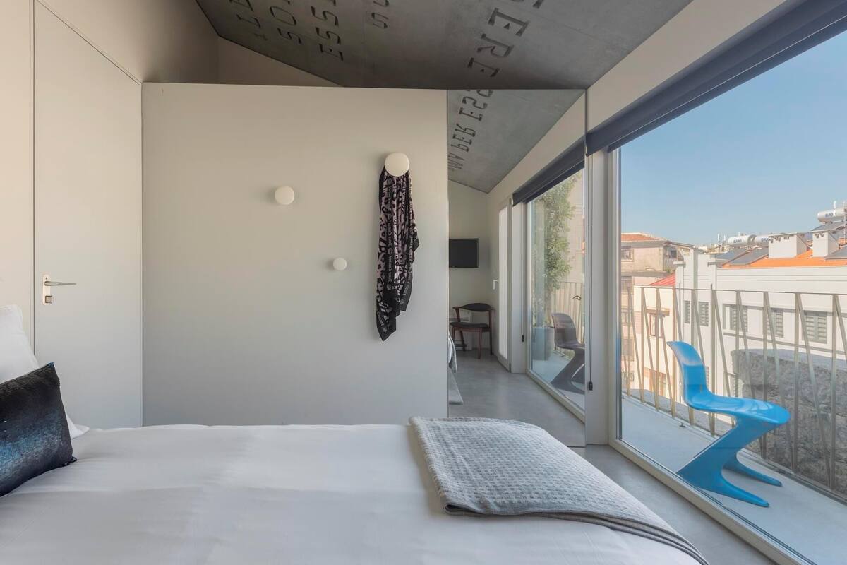 Un dormitorio moderno con una cama grande, vistas a la ciudad y un diseño de techo original.