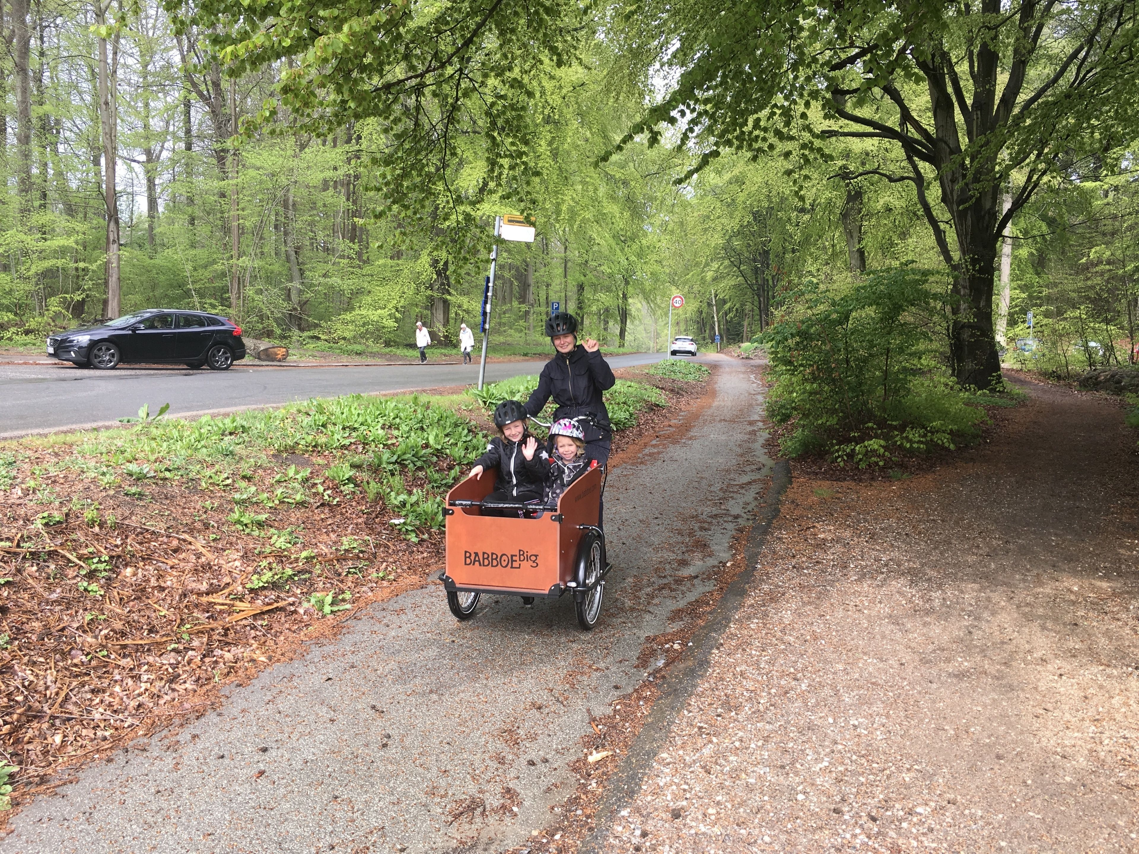 Een geplaveid pad naast een weg, met een voertuig en voetgangers.
