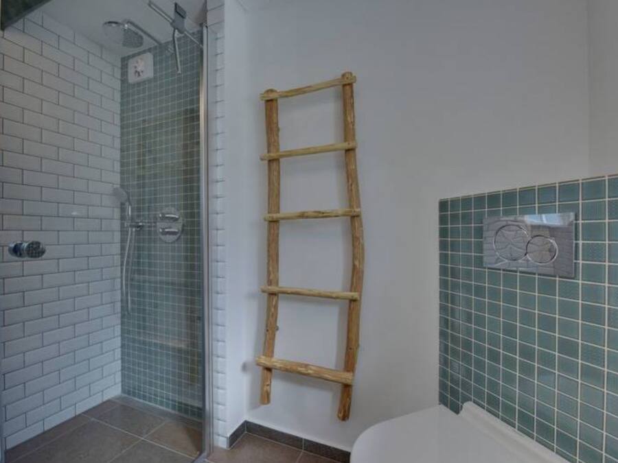 Ein Badezimmer mit Dusche, einer Holzleiter und einer Toilette.