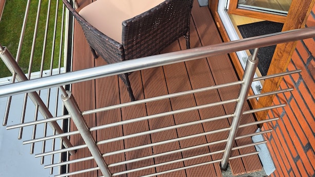 A balcony with a table and chairs, a glass door, and a metal railing. - Vacation apartment Leer-Stadtmitte 15131 - Holiday apartment Leer-Stadtmitte (Leer (Ostfriesland))