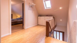 A loft bedroom with a sloped ceiling, a skylight, a wooden floor, a bed, a desk, and a chair. - Vacation apartment Leer-Stadtmitte 15131 - Holiday apartment Leer-Stadtmitte (Leer (Ostfriesland))