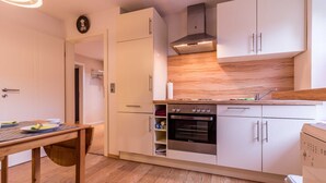 A modern kitchen with white cabinets, a built-in oven, and a wooden countertop. - Vacation apartment Leer-Stadtmitte 15131 - Holiday apartment Leer-Stadtmitte (Leer (Ostfriesland))