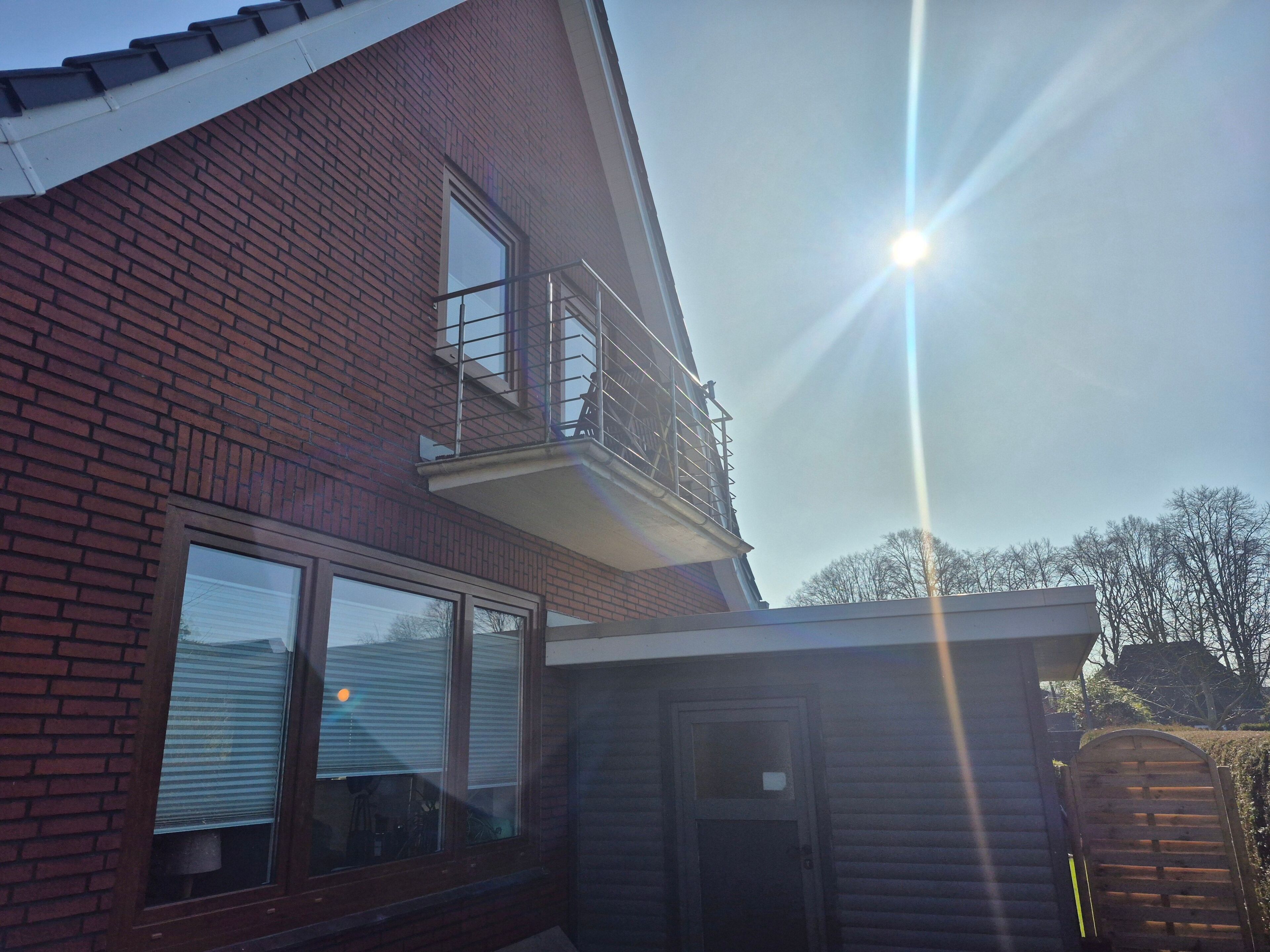 Ein zweistöckiges Backsteingebäude mit Balkon und Garage, bewölkter Himmel.