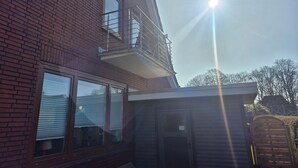 A two-story brick building with a balcony, a garage door, and a clear sky. - Vacation apartment Leer-Stadtmitte 15131 - Holiday apartment Leer-Stadtmitte (Leer (Ostfriesland))