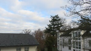 A residential area with a house featuring a tiled roof and a white facade. - 2-room apartment - House Quisisana - Apartment 45496 (Göhren)