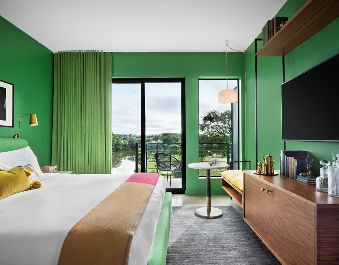 A hotel room with a large bed, a desk, a chair, and a TV.