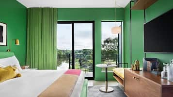 A hotel room with a large bed, a desk, a chair, and a TV.