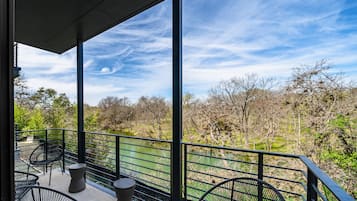 A balcony with metal railings, two black wicker chairs, and a small round table.