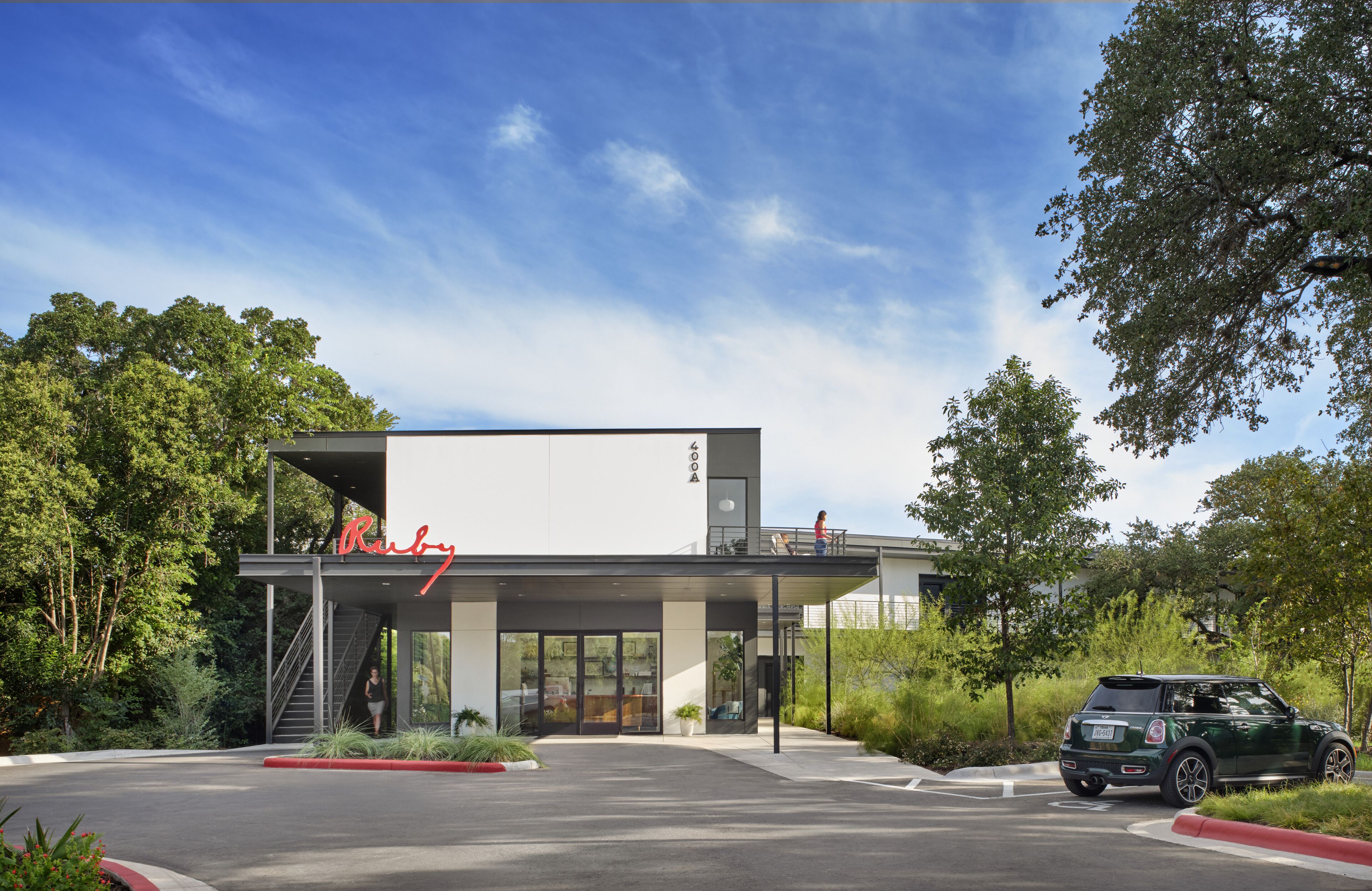 A modern building with a prominent sign, a covered entrance, and a parking area.