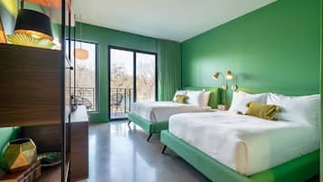 A modern hotel room with two beds, a wooden desk, and a view of the outdoors.