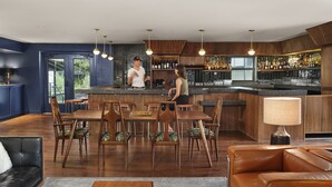 A modern bar area with a counter, seating, and a bar stocked with bottles. - The Ruby Hotel (Round Rock)