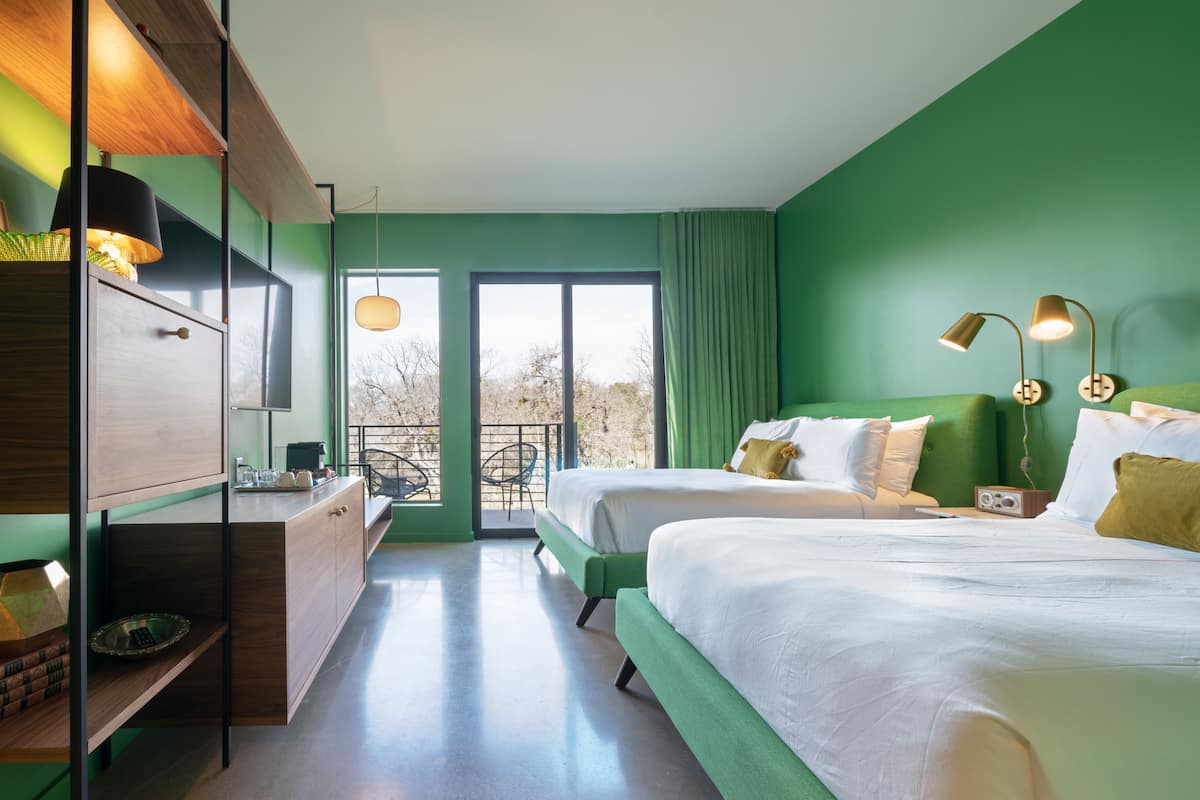 Ein modernes Hotelzimmer mit zwei Betten, einem Schreibtisch und einem Balkon mit Blick.