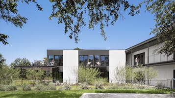 A modern two-story house with a swimming pool, surrounded by a well-maintained garden and a clear blue sky.