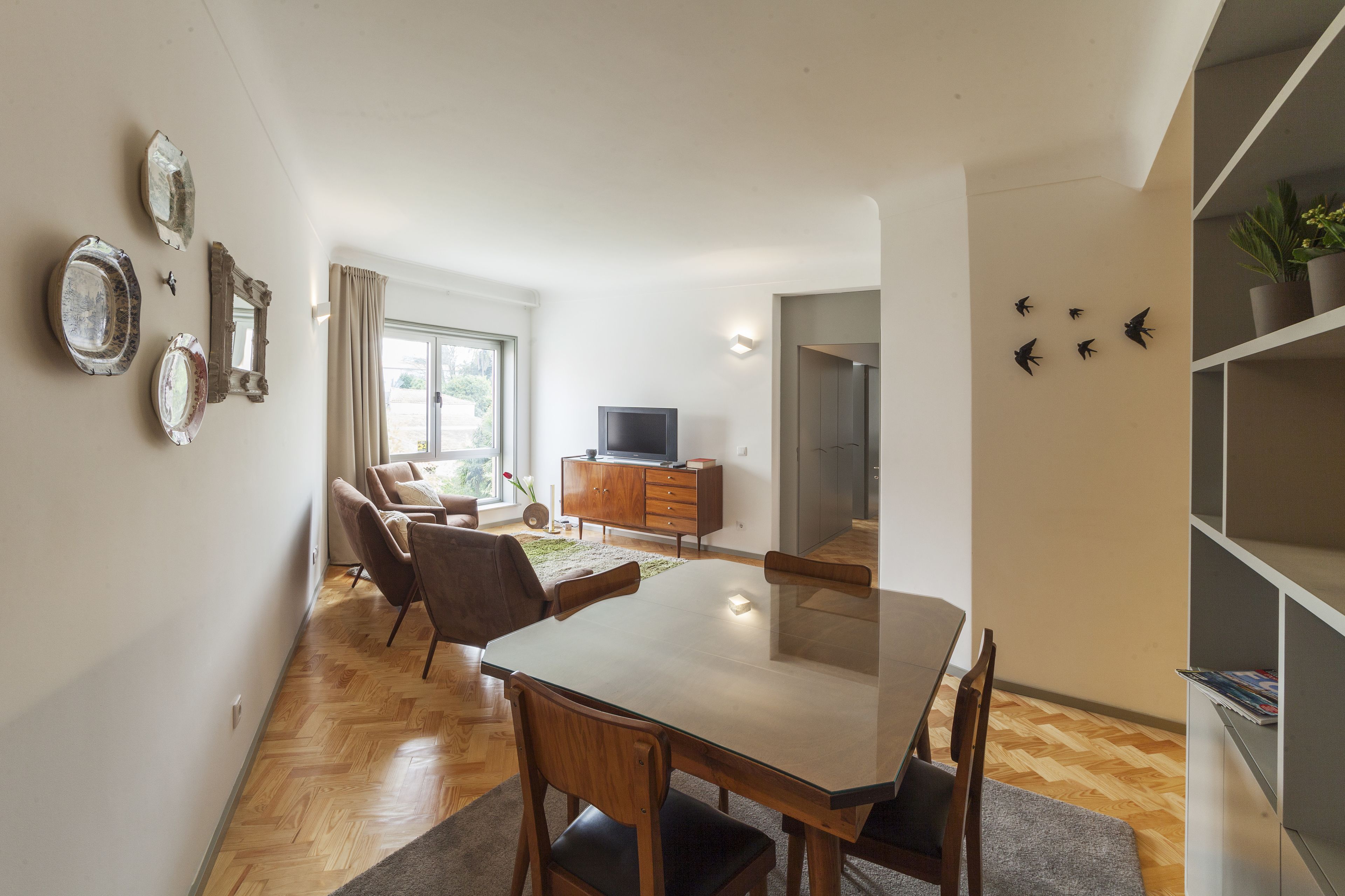 A modern living room with a dining area, a TV, and a bookshelf.