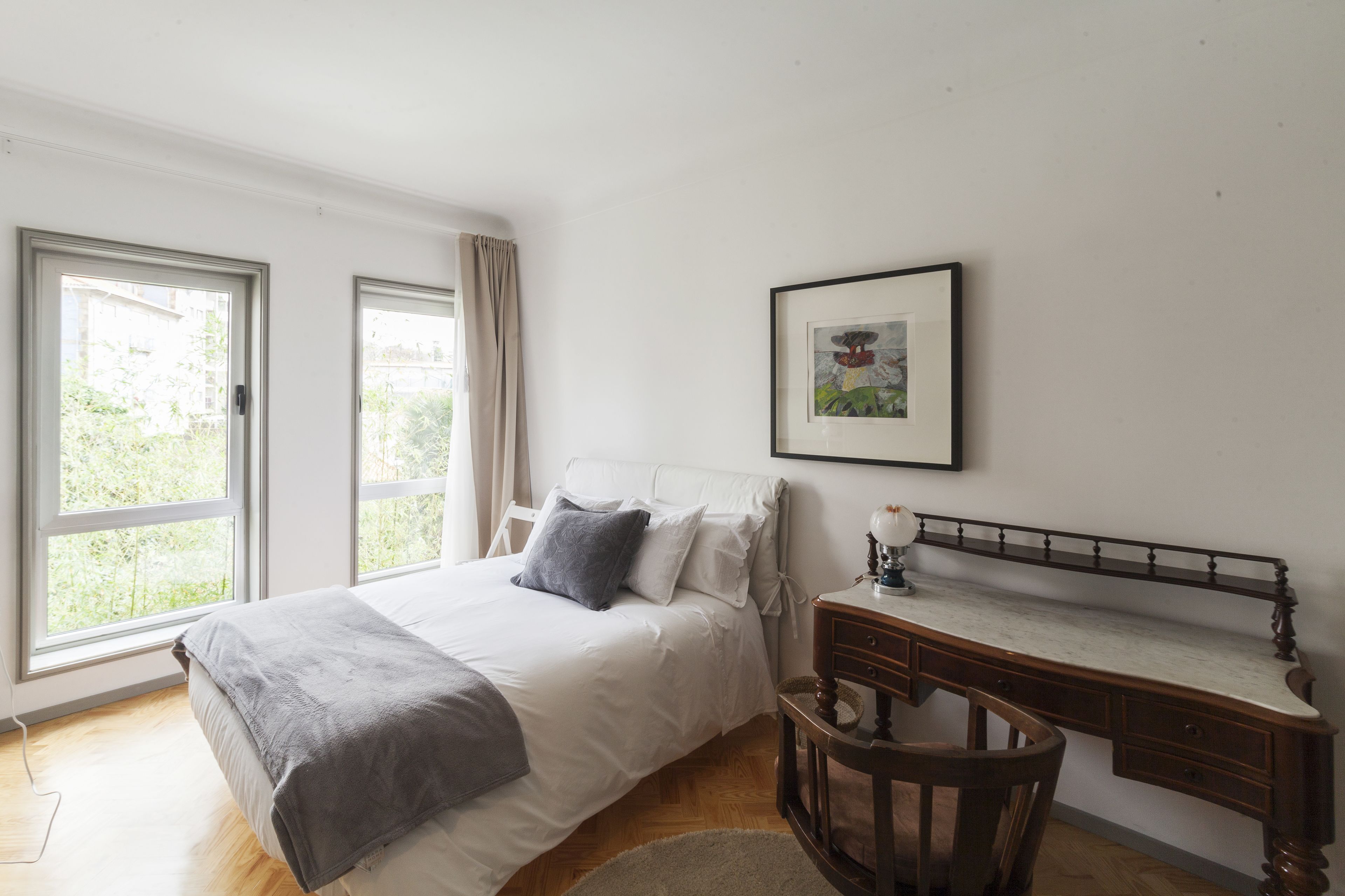 A bedroom with a bed, a desk, and a window.