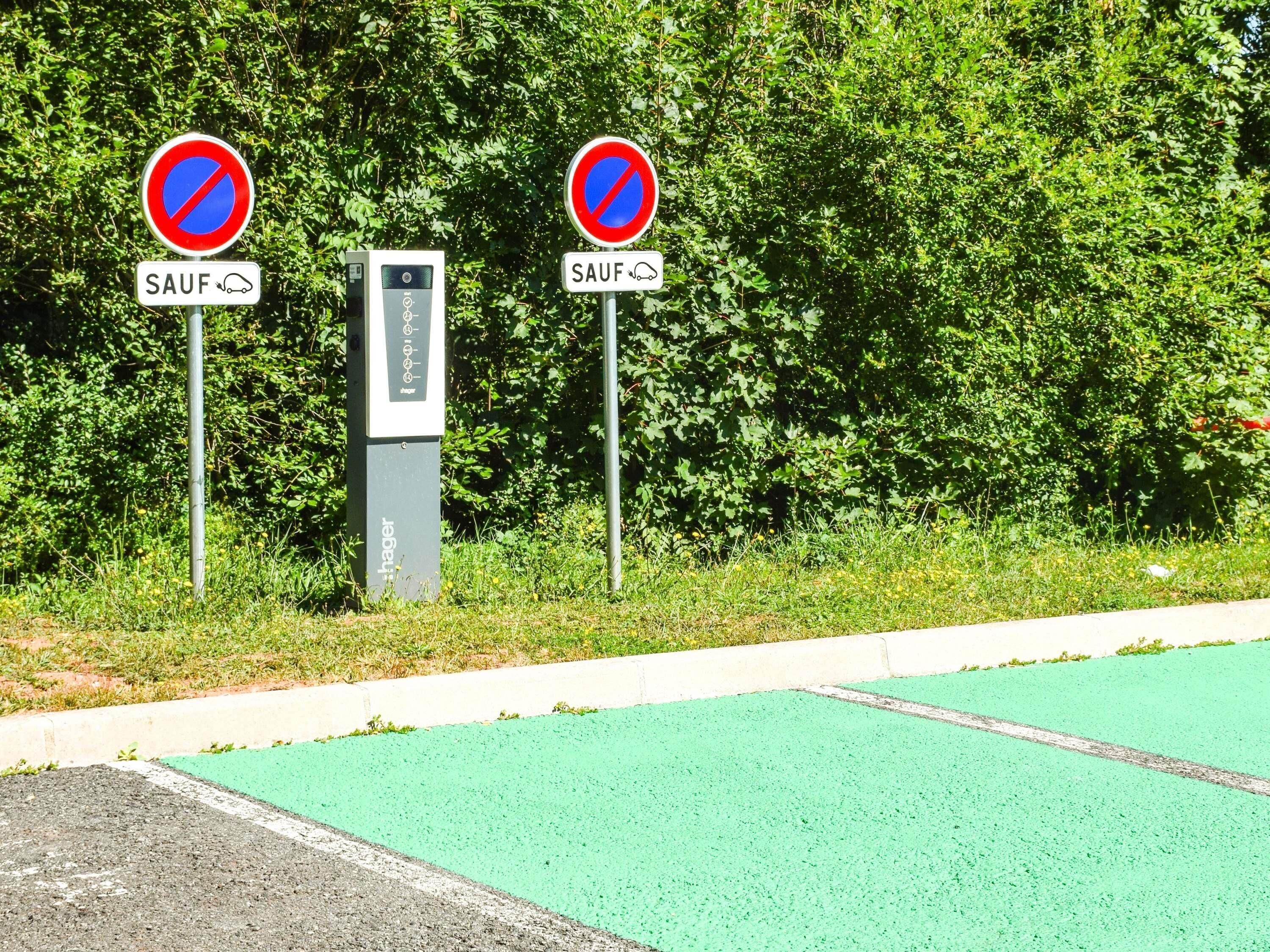 Een verboden parkeersign met een 'SAUF' bordje eronder, een parkeerautomaat en een groene fietspad.