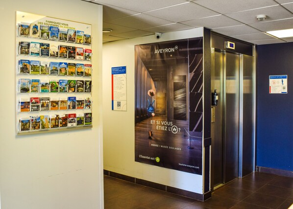 Un passadís amb un cartell de viatge, una presentació de llibres i un ascensor.