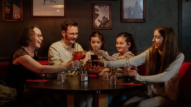 A group of people seated around a table in a dimly lit room with framed pictures on the walls. - Ibis Budget Rodez (Rodez)