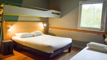 A bunk bed room with a wooden headboard, bedside lamps, and a window with a view of trees.