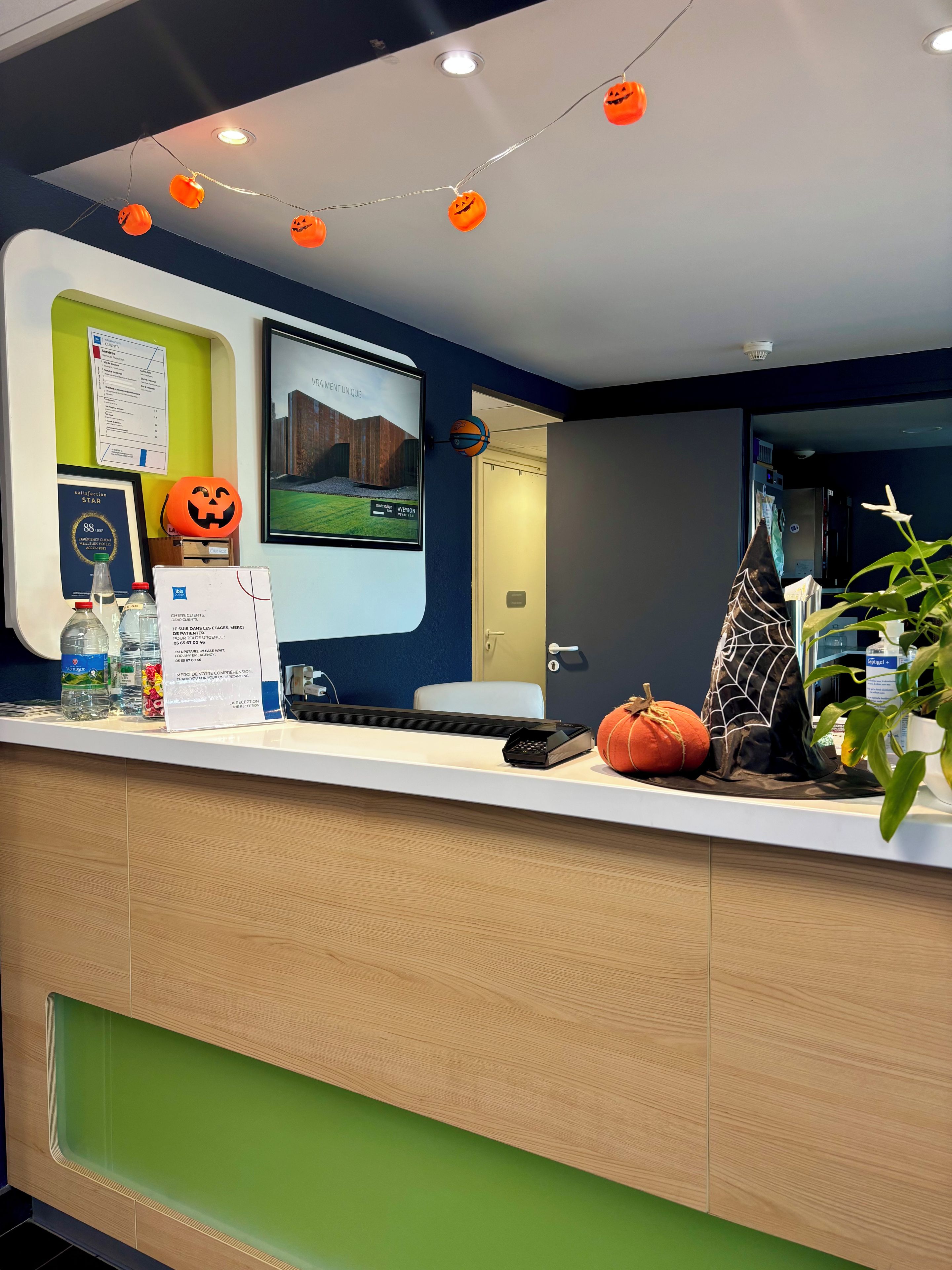 Bancada de recepção decorada para o Halloween, um certificado emoldurado e uma tela digital exibindo uma imagem de um edifício.