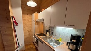 Cuina compacta amb armaris de fusta, un rentapeus d'acer inoxidable i una cafetera.