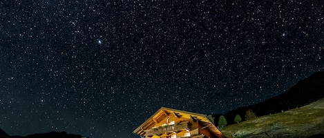 A two-story building with balconies, a parking area, and a starry night sky.