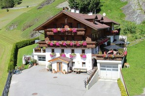 Una cabaña con balcones decorados con flores, un garaje y un pequeño espacio al aire libre para sentarse.