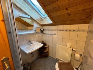 Un baño con tragaluz, lavamanos, inodoro y zona de ducha.