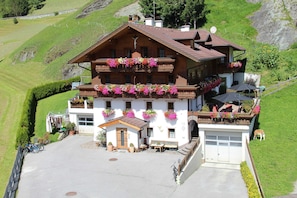 A chalet with balconies adorned with flowers, a garage, and a small outdoor seating area.