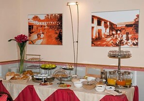 A breakfast buffet with various food items and a flower vase.